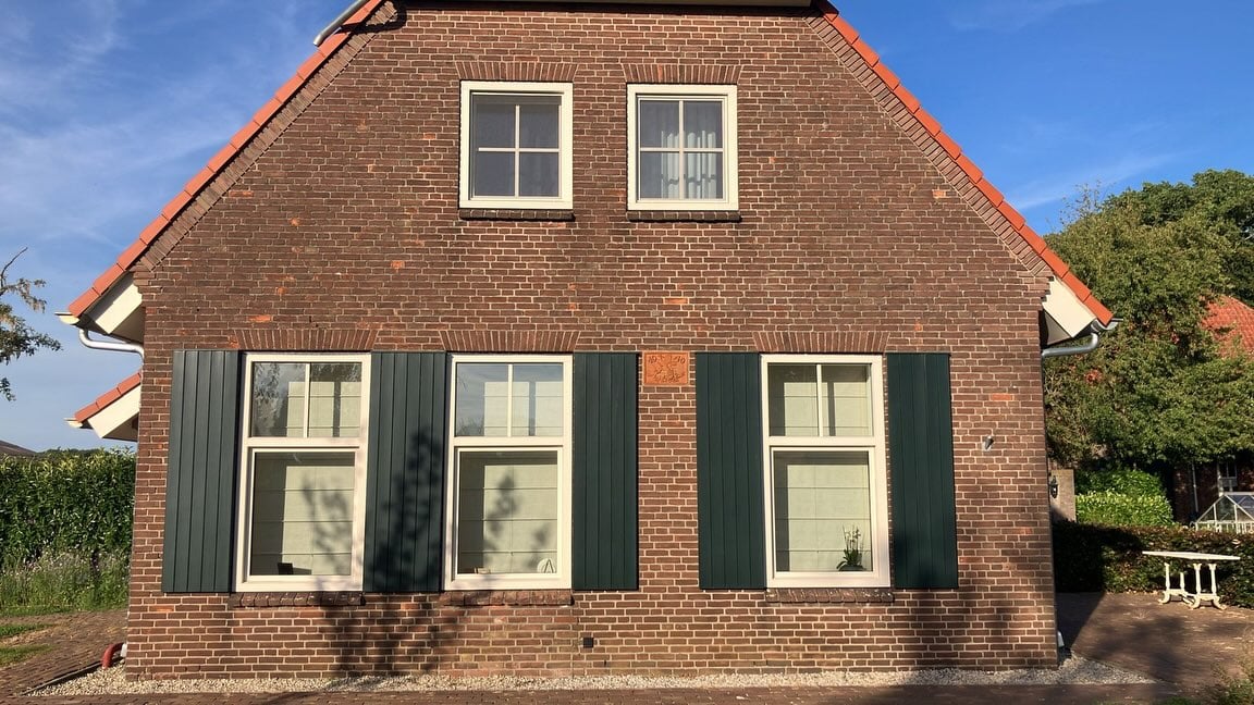 Gevel van de boerderij in Mill na de gevelrenovatie: opnieuw gevoegd, met groene luiken